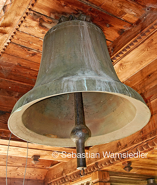 Kleinste Mindener Domglocke. Sie hängt mit weiteren Glocken unter einem Vordach der russisch-orthodoxen Holzkirche.